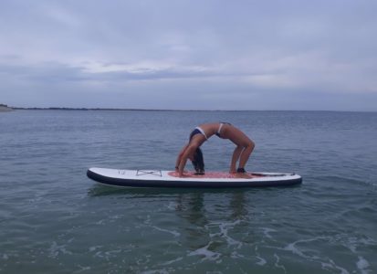 Pratique de la posture de yoga Chakrasana sur un paddle